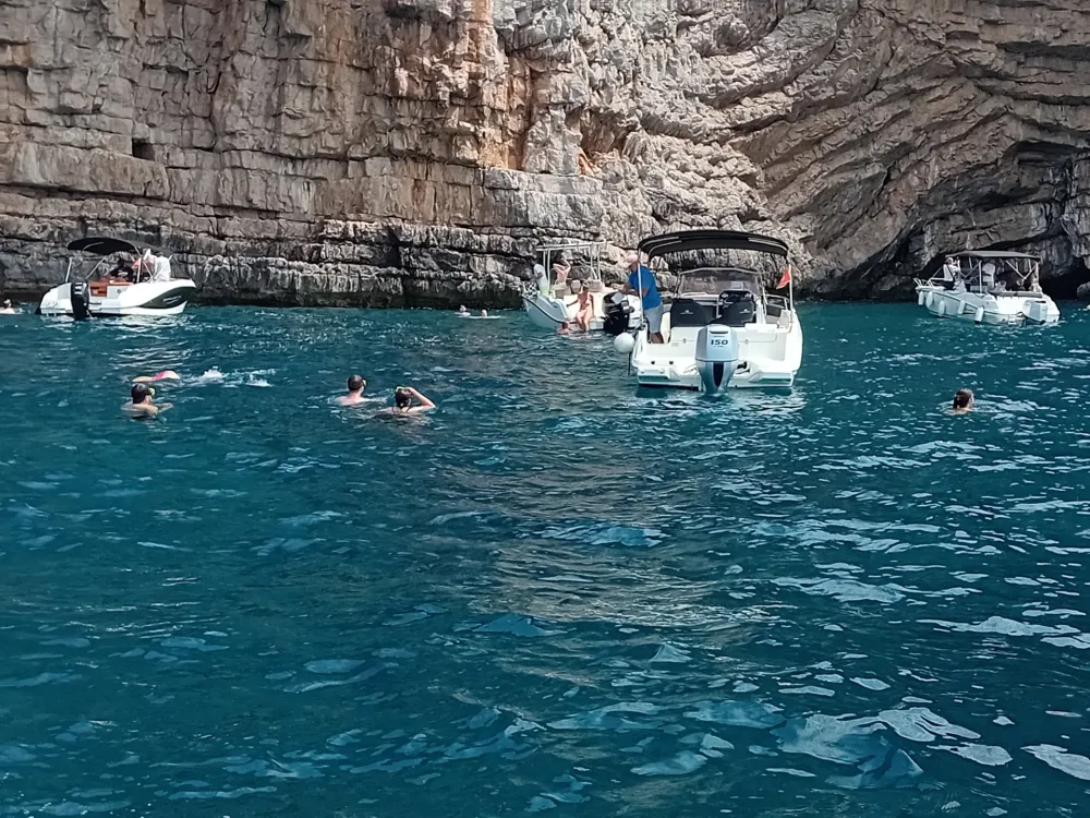 бројне барке и туристи у мору испред Плаве шпиље