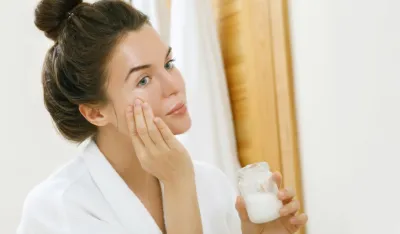 Woman is moisturising her skin with a coconut oil