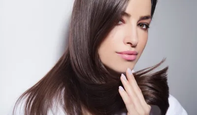 beautiful young woman holding her healthy and shiny hair, studio white